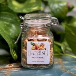 Clear jar with hinge style lid with tea inside on a blue calcite charging plate.