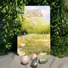 four stones on a gray cloth base with gridding card and foliage in the background