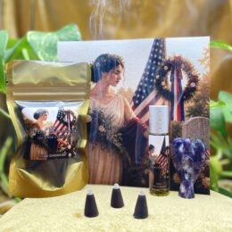 A Memorial Day themed altar set shows a gold pouch of incense cones, three burning cones, a roller perfume, an amethyst angel carving, and a canvas of a woman before an American flag and wreath.
