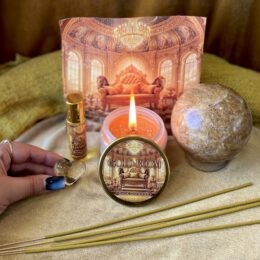 A gold themed altar display featuring the Gold Room candle, perfume, citrine sphere, incense sticks, and citrine heart arranged before an ornate golden throne backdrop.